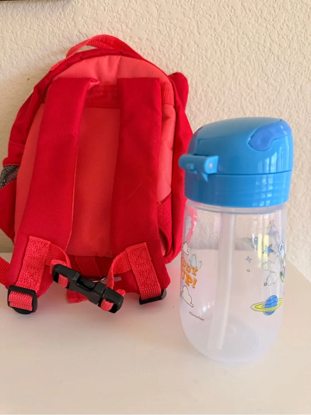 Skip Hop Zoo Mini Backpack with Blue and Toy Story Sippy Cup.